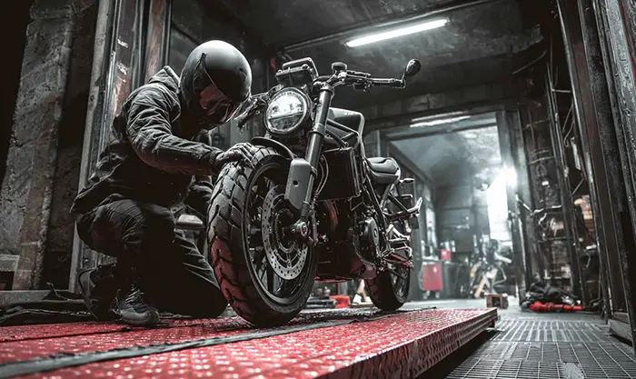 Motard sécurisant une moto levée avec sangle sur plateforme stable