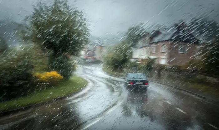 Voiture dans un virage sous pluie battante, tenue de route Michelin Primacy 4