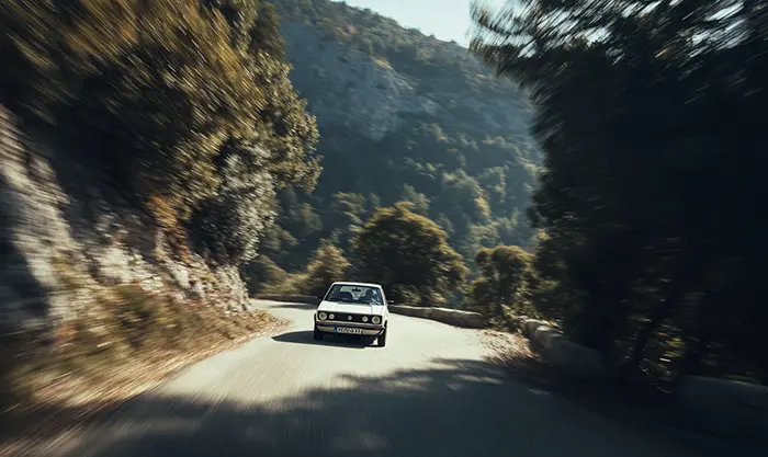 Volkswagen Golf I GTI roulant sur route de montagne