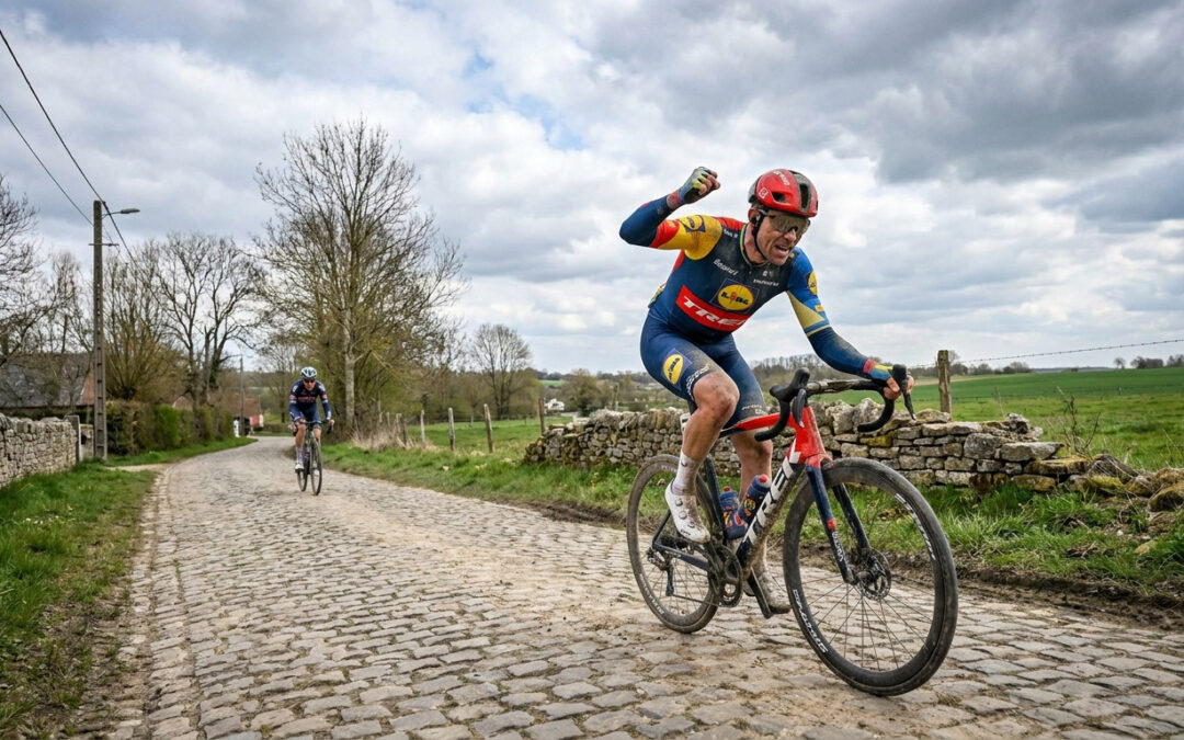 Un cycliste de l'équipe Lidl-Trek célèbre sa victoire en levant le poing sur une route pavée de Paris-Roubaix.