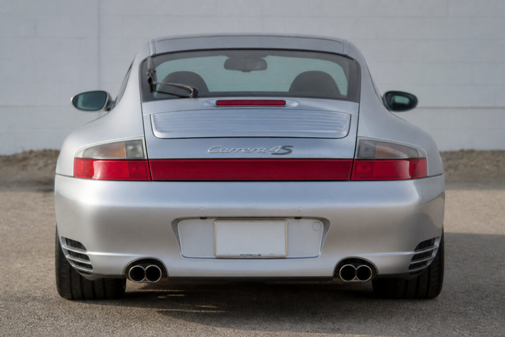 Vue arrière d'une Porsche 996 Carrera 4S argentée avec son bandeau lumineux distinctif.